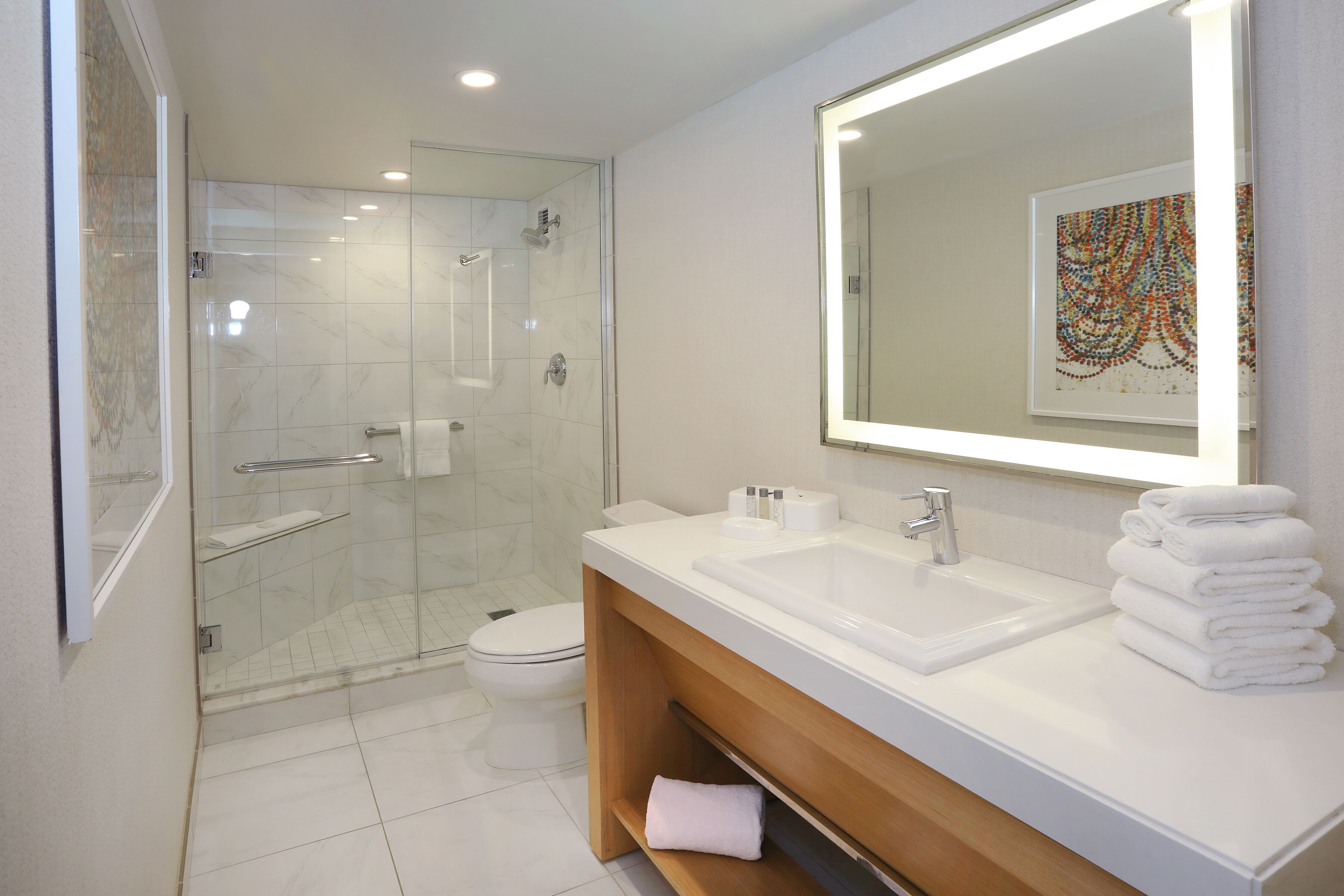 A modern bathroom with a glass-enclosed shower, a white sink, and a large mirror.