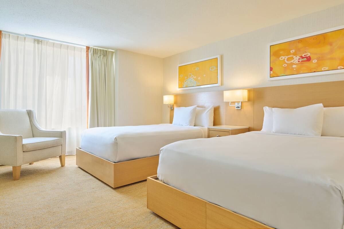 Ett hotellrum med två sängar, en stol och konstverk på väggarna.
