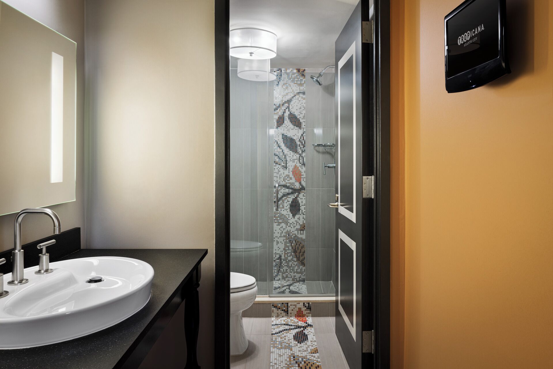 A modern bathroom with a glass-enclosed shower, a white sink, and a toilet.