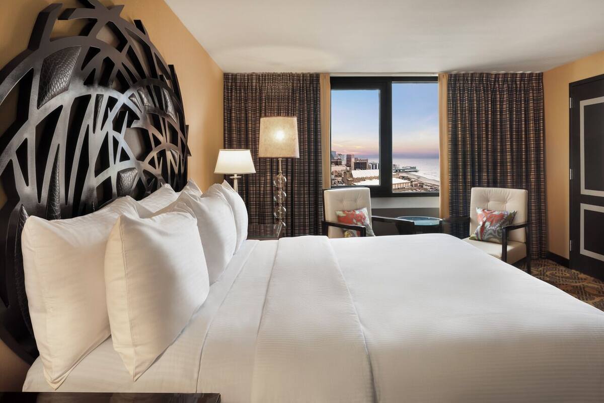Ett hotellrum med en stor säng, utsikt över staden och en dekorativ väggdekoration.
