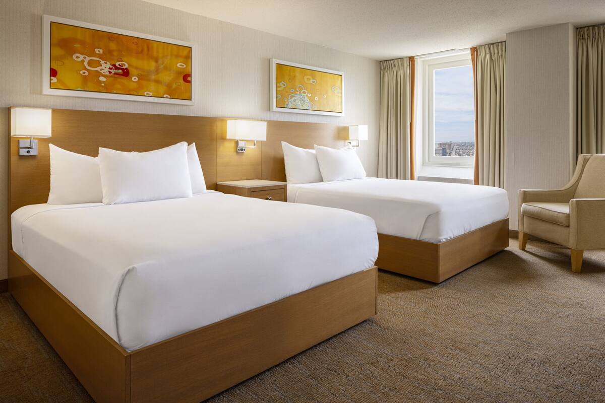 Ett hotellrum med två sängar, en stol och konstverk på väggarna.