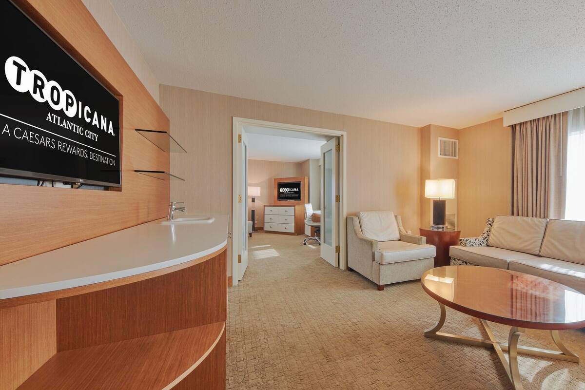 Ett hotellrum med en receptionsdisk, en soffa, ett soffbord, en stol och en skrivbordslampa.