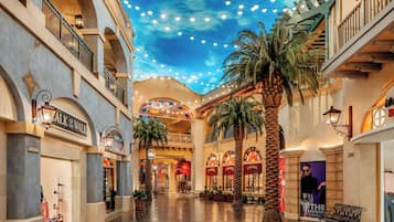 A shopping mall with multiple levels, palm trees, and string lights.
