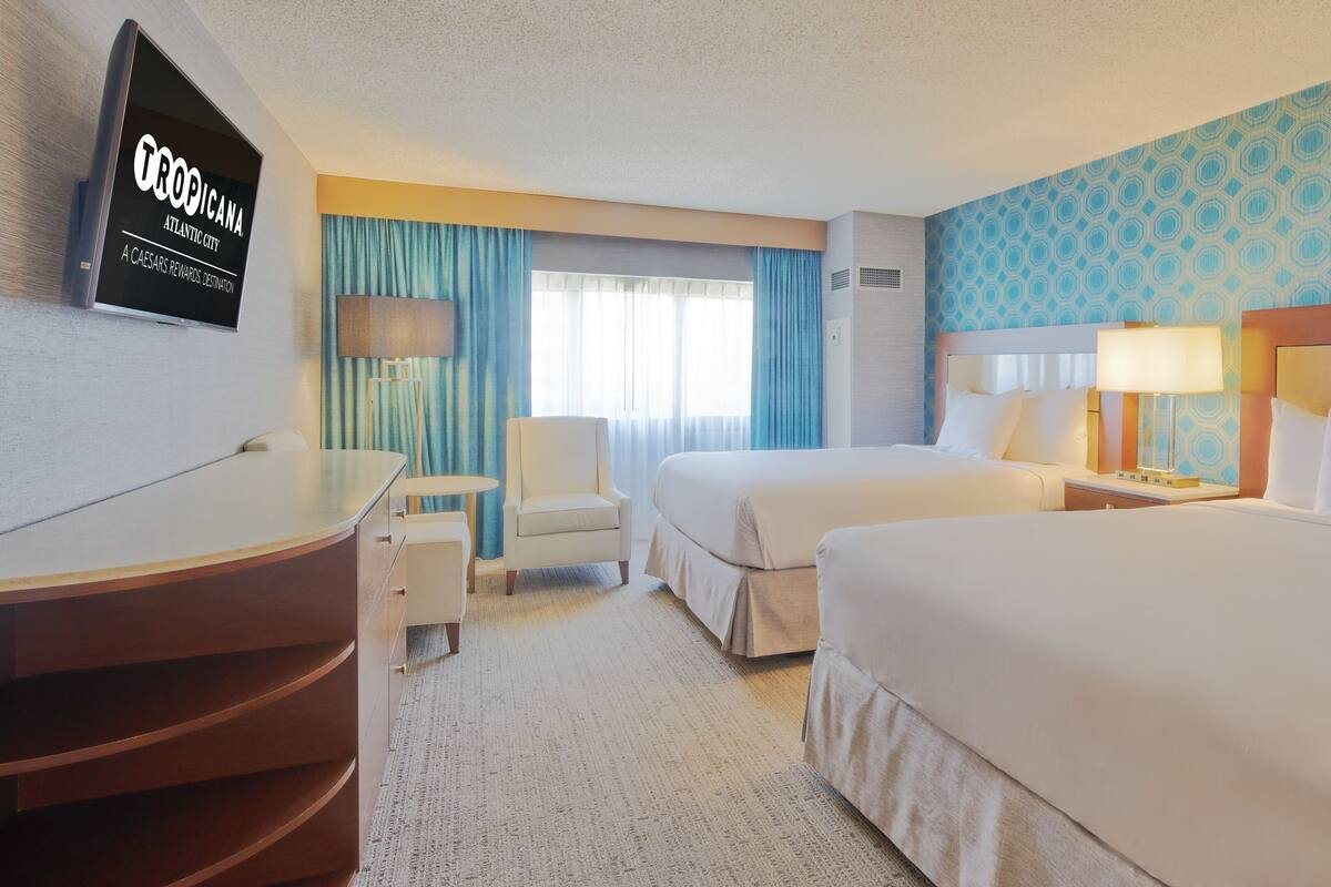 Ett hotellrum med två sängar, ett skrivbord, en stol och en tv som visar Tropicana-logotypen.
