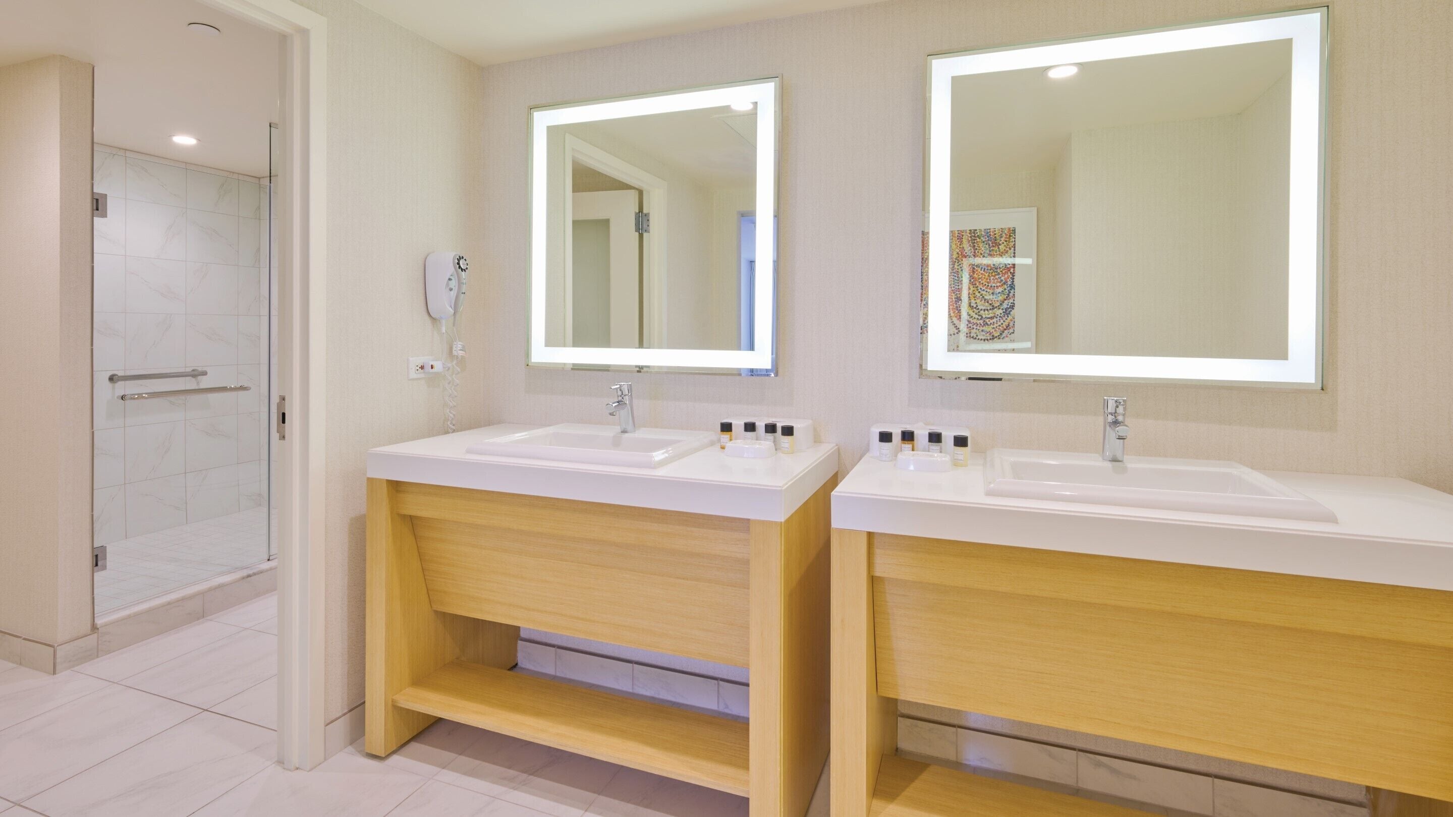 Une salle de bain moderne avec deux lavabos, une douche et un sèche-cheveux.