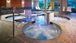Ein Wellnessbereich mit Whirlpools, Liegestühlen und Steinboden.