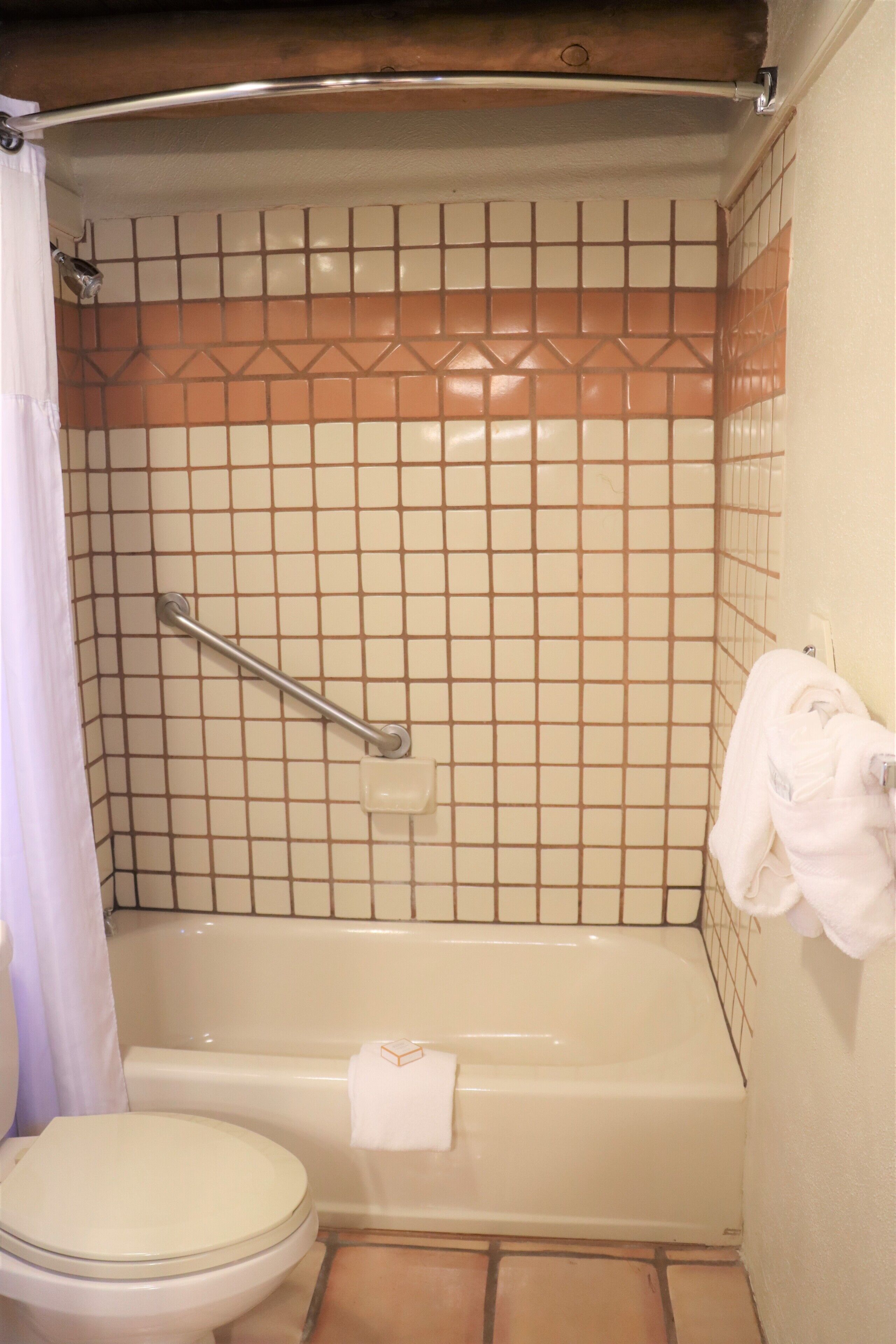 A bathroom with a bathtub, toilet, and a shower curtain.