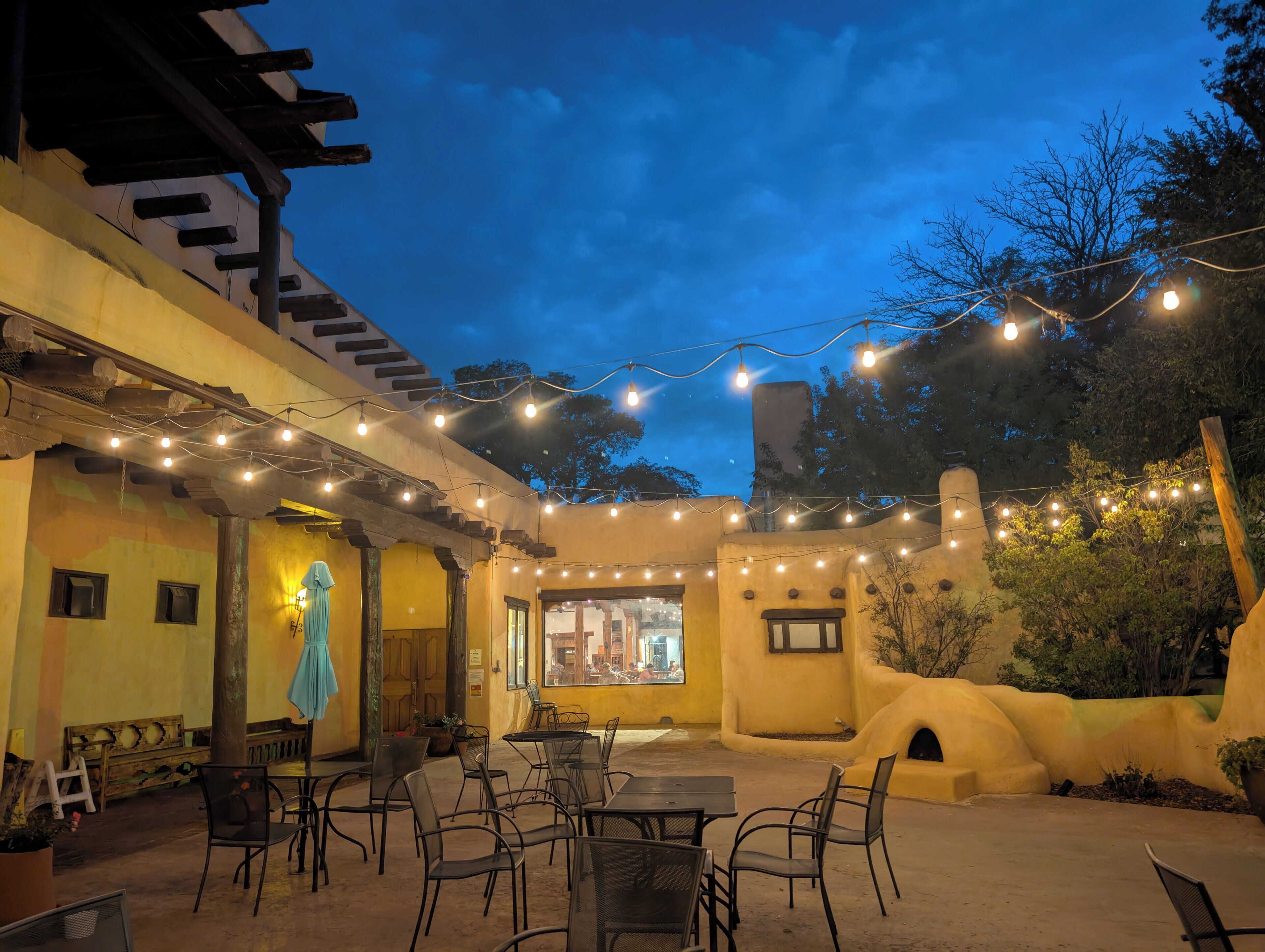 An outdoor dining area with string lights, tables, and chairs.