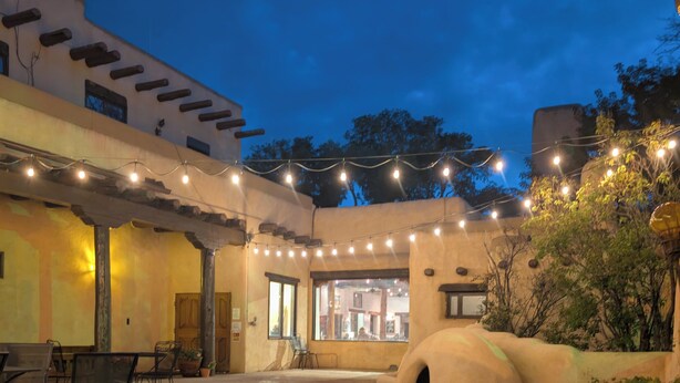 An outdoor courtyard with a seating area, a small structure, and string lights. - Sagebrush Inn & Suites (Taos)