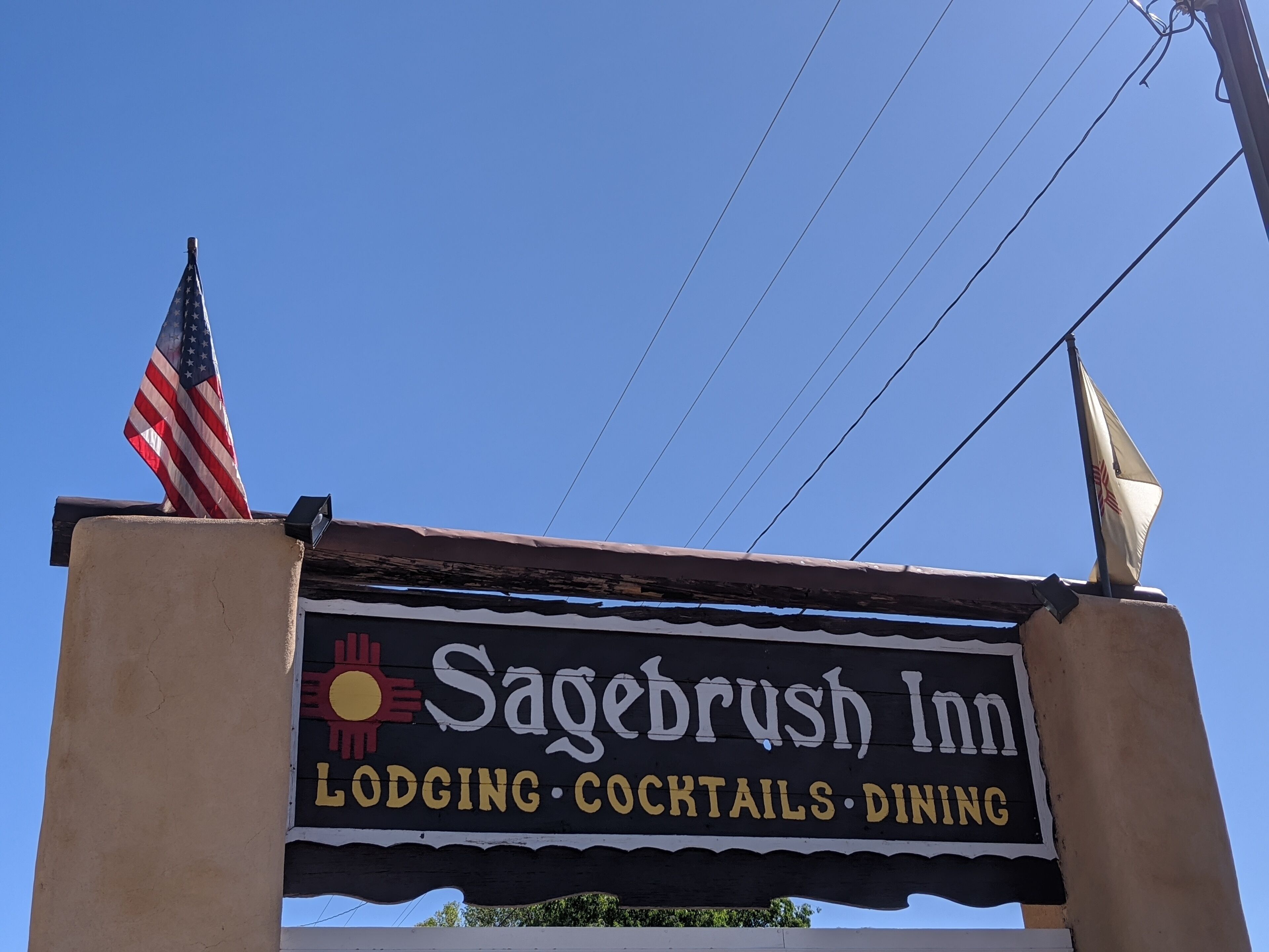 Une enseigne indiquant l’établissement Sagebrush Inn et annonçant qu’il propose des chambres, des cocktails et un service de restauration.