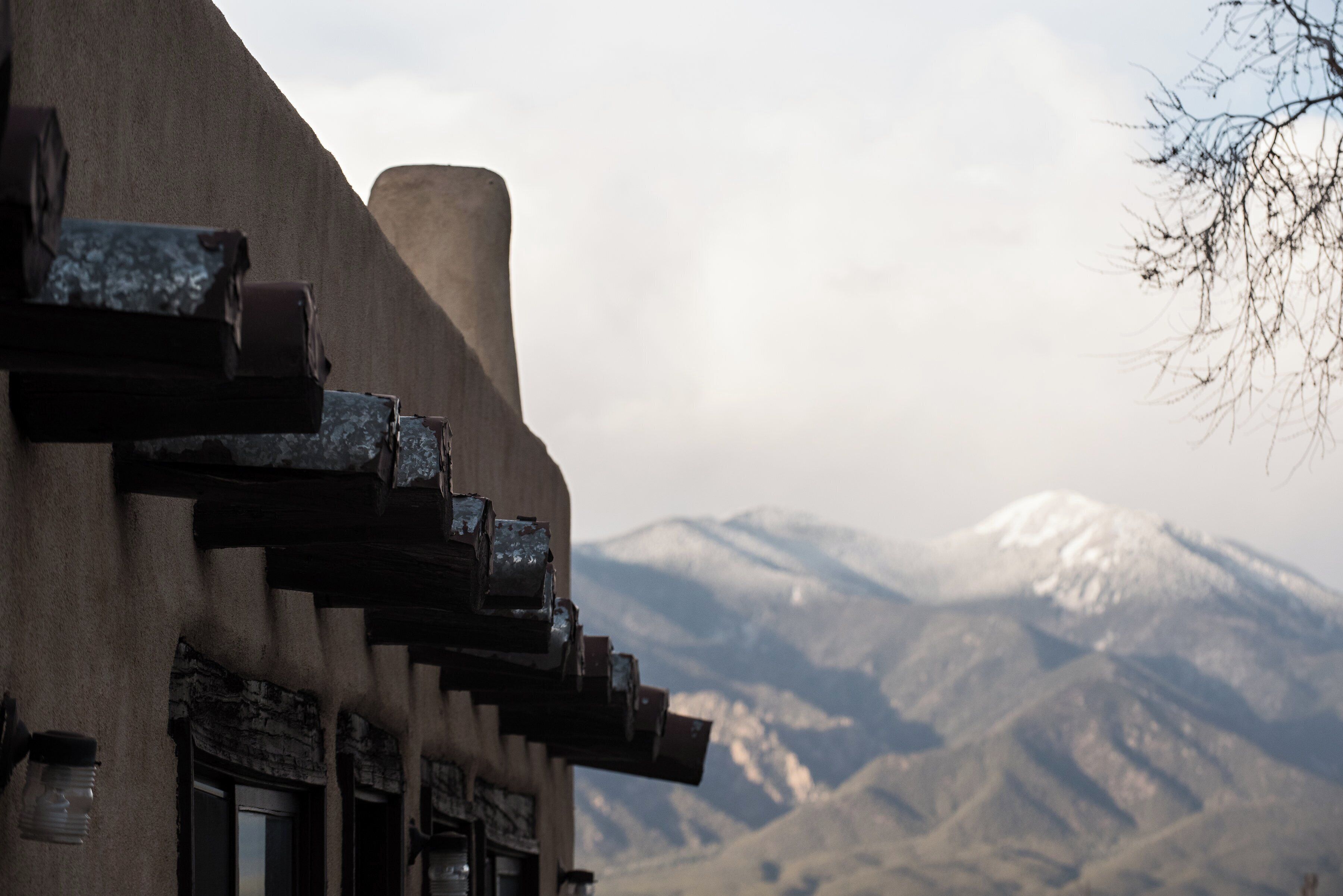 A building with a unique architectural design, featuring a prominent chimney and a view of snow-capped mountains in the background.