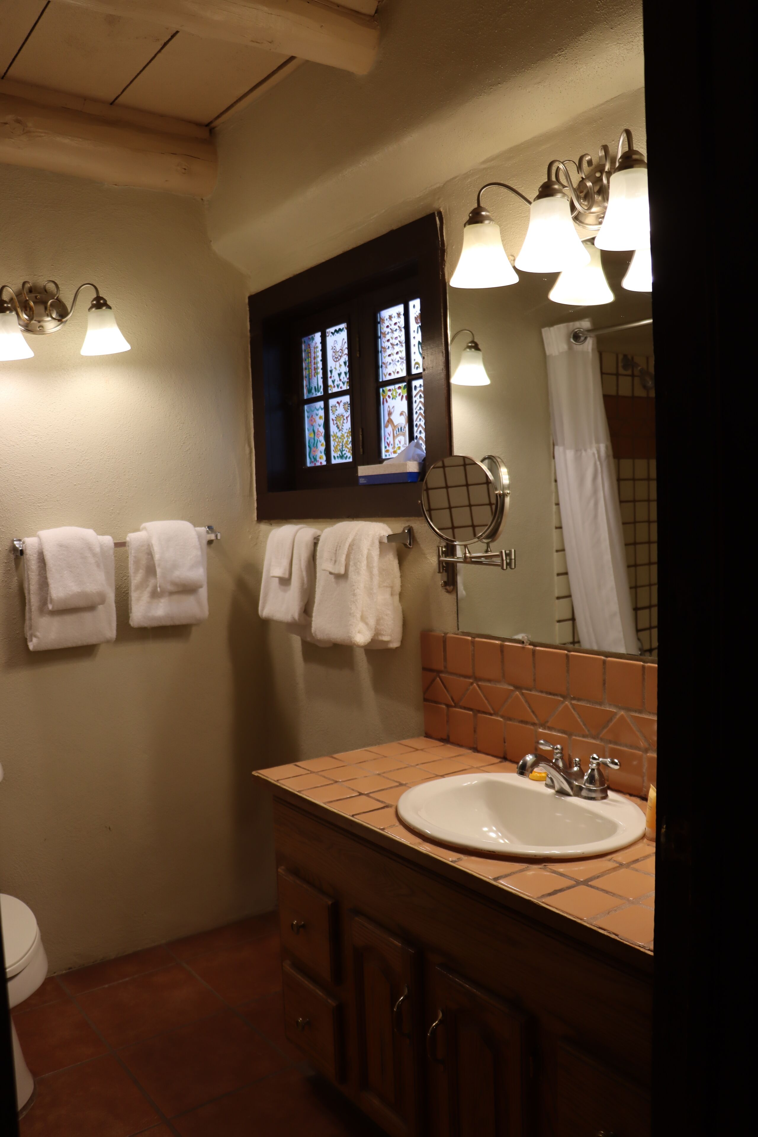 A bathroom with a sink, mirror, and towels on the wall.