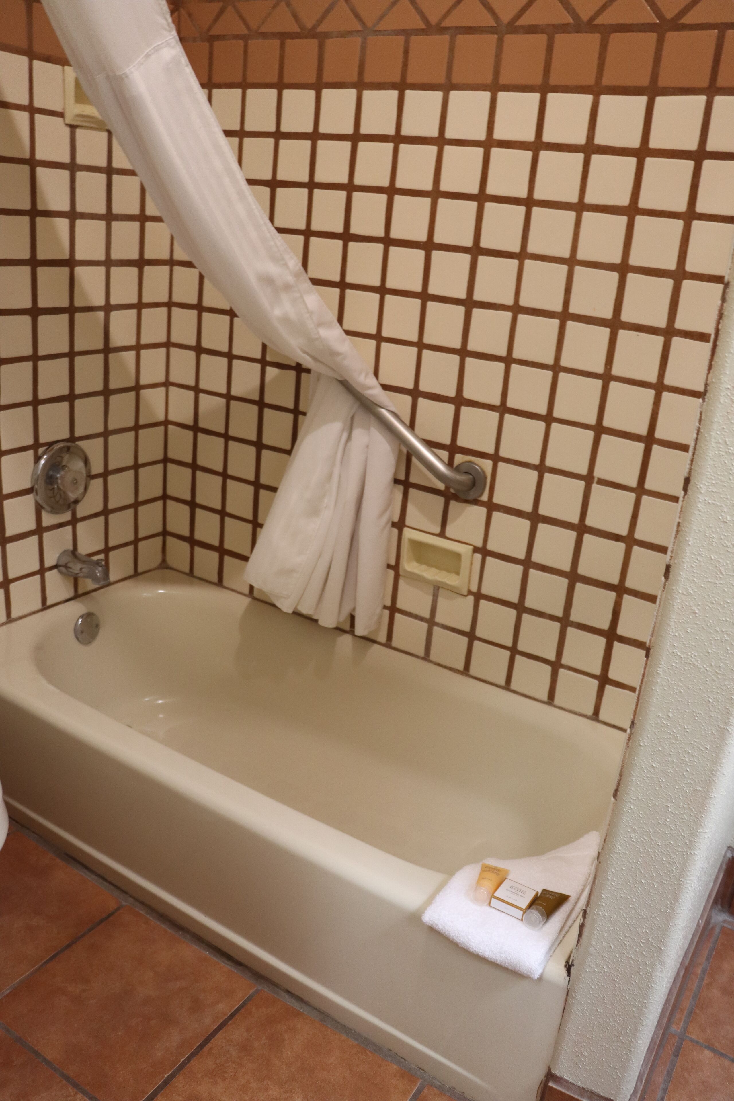 A bathroom with a bathtub, a shower curtain, and a towel rack.