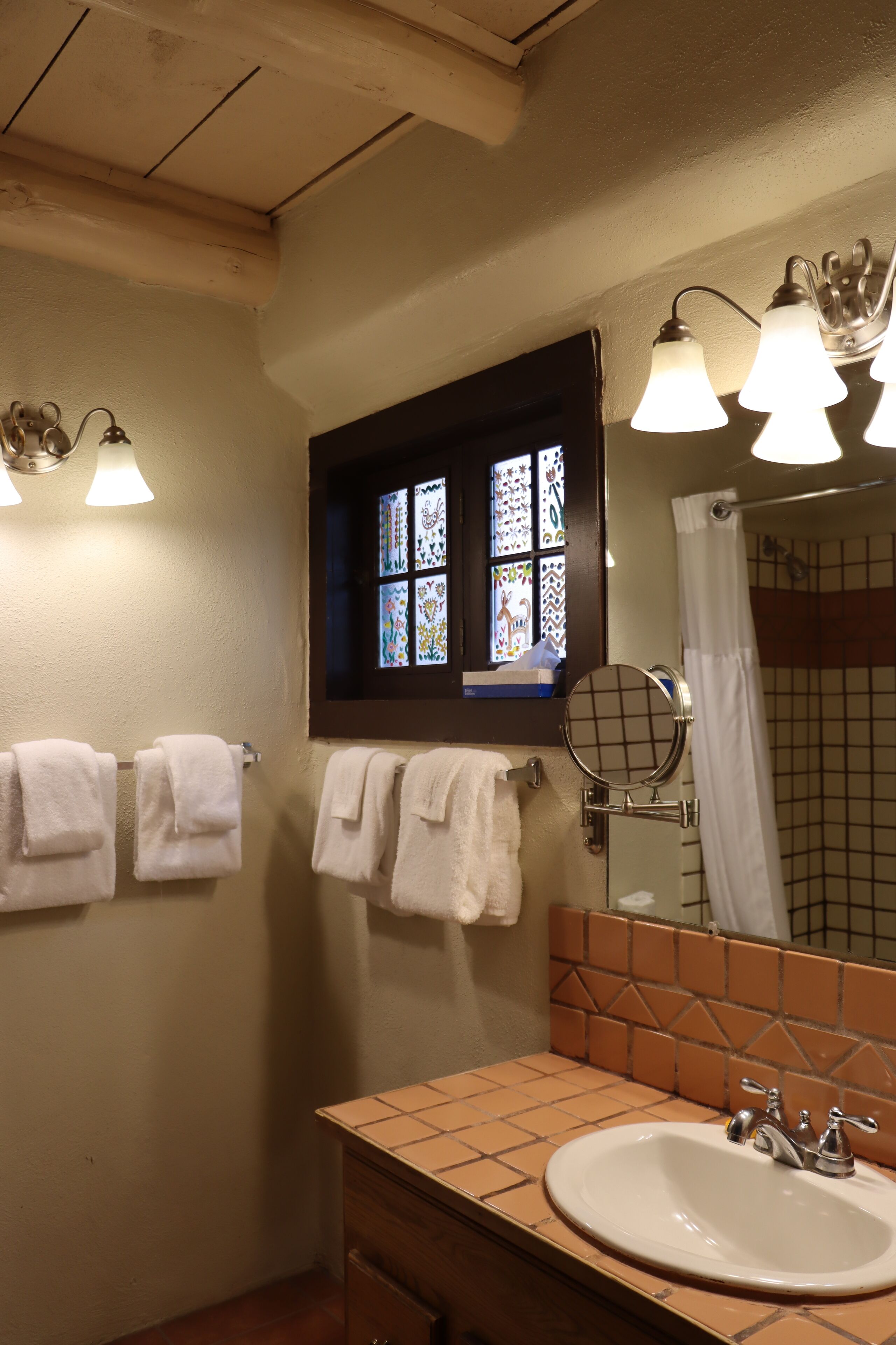 Un baño con un lavamanos blanco, una ventana con vidrieras y una cortina de ducha.