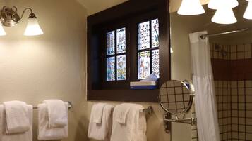 A bathroom with a white sink, a window with stained glass, and a shower curtain.