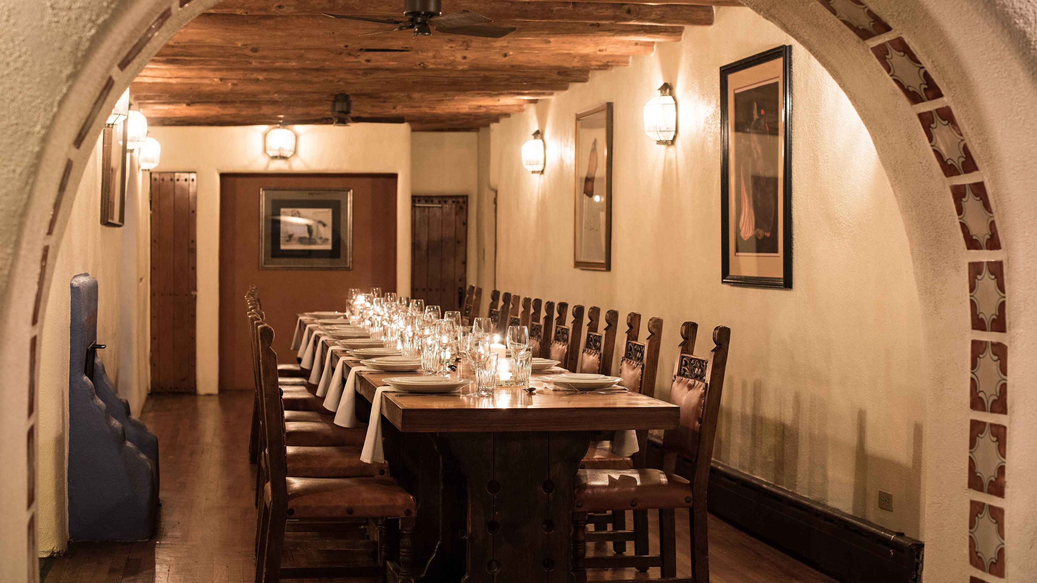 A long dining table set for a meal in a room with wooden beams and arched ceilings.