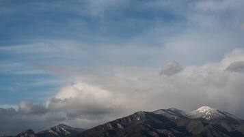 A mountain range with snow-capped peaks and a cloudy sky.