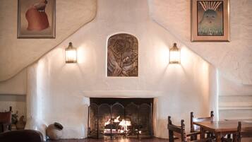 Una chimenea con arco de piedra, dos faroles colgantes y una obra de arte enmarcada encima.