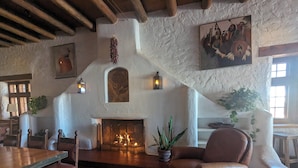A rustic interior with a fireplace, wooden furniture, and stone walls. - Sagebrush Inn & Suites (Taos)