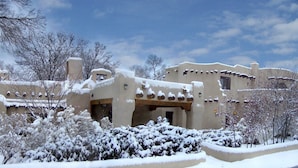 A snow-covered building with a unique architectural style, surrounded by snow-laden trees. - Sagebrush Inn & Suites (Taos)