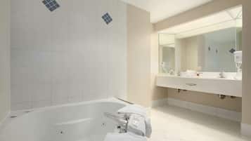 A modern bathroom with a large bathtub, a double sink vanity, and a large mirror.