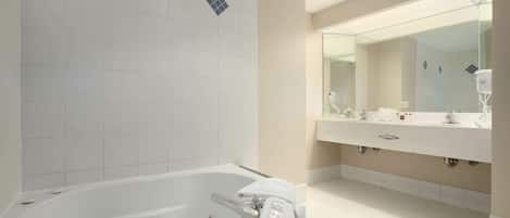 Une salle de bain moderne avec une grande baignoire, un meuble-lavabo à deux vasques et un grand miroir.
