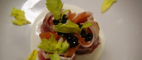 Une assiette contenant une portion de jambon de Parme, du caviar noir, et décorée de persil.