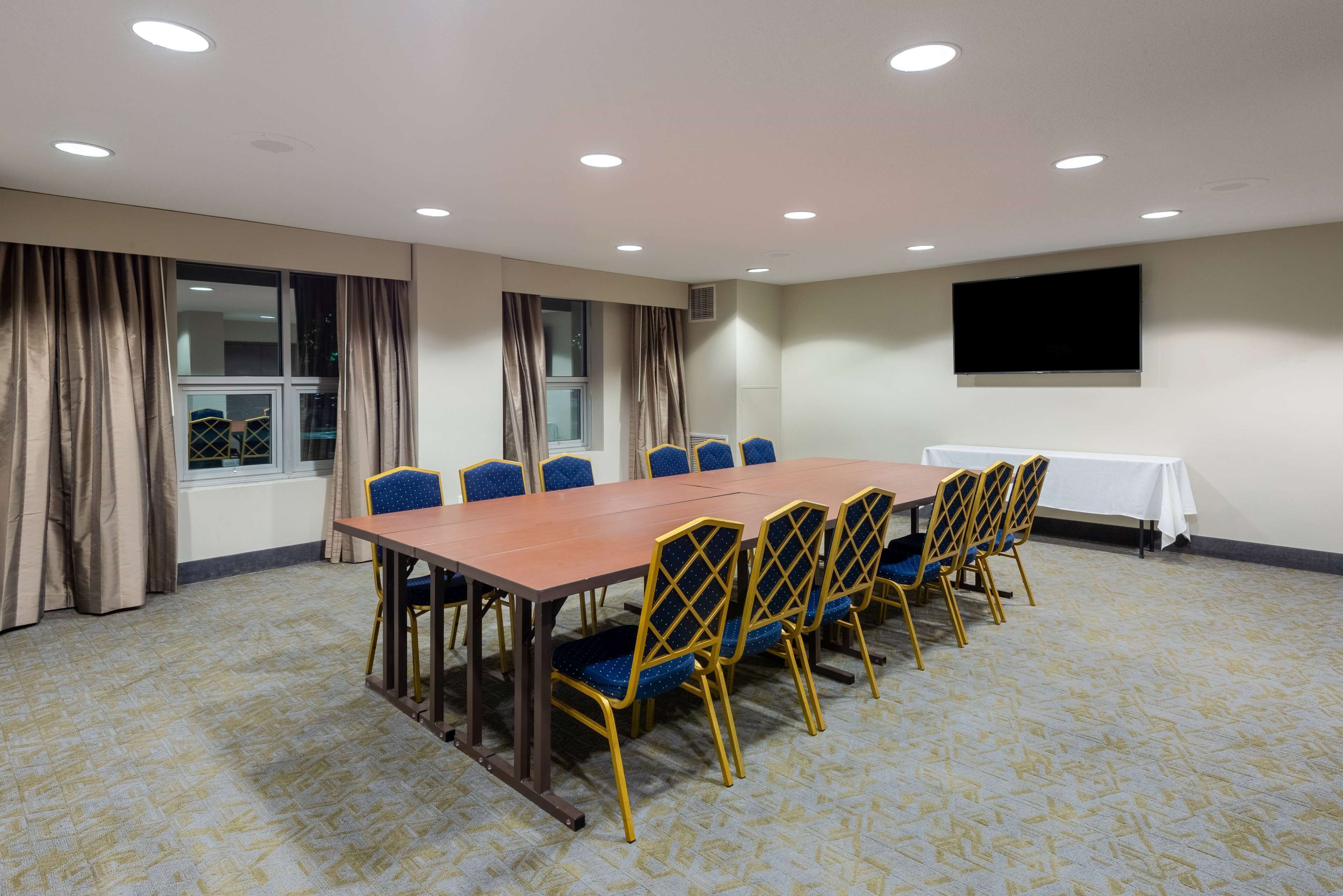 A conference room with a long table, blue chairs, and beige curtains.