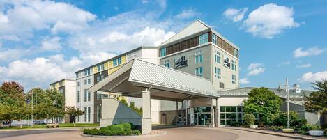 A modern hotel with a covered entrance, multiple floors, and a prominent sign.