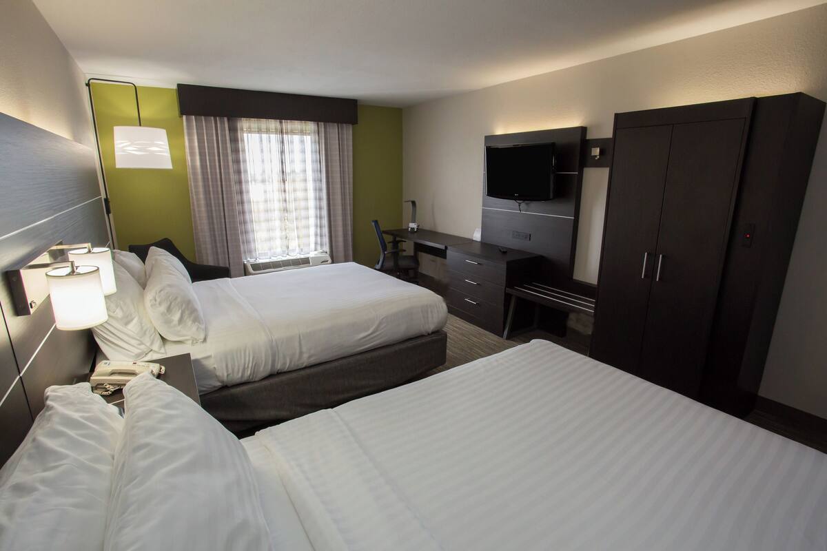 Hotellihuone, jossa on kaksi sänkyä, työpöytä, tuoli, televisio ja vaatekaappi.