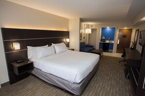 Une chambre d’hôtel avec un grand lit, des tables de chevet, un bureau, une chaise et un miroir.
