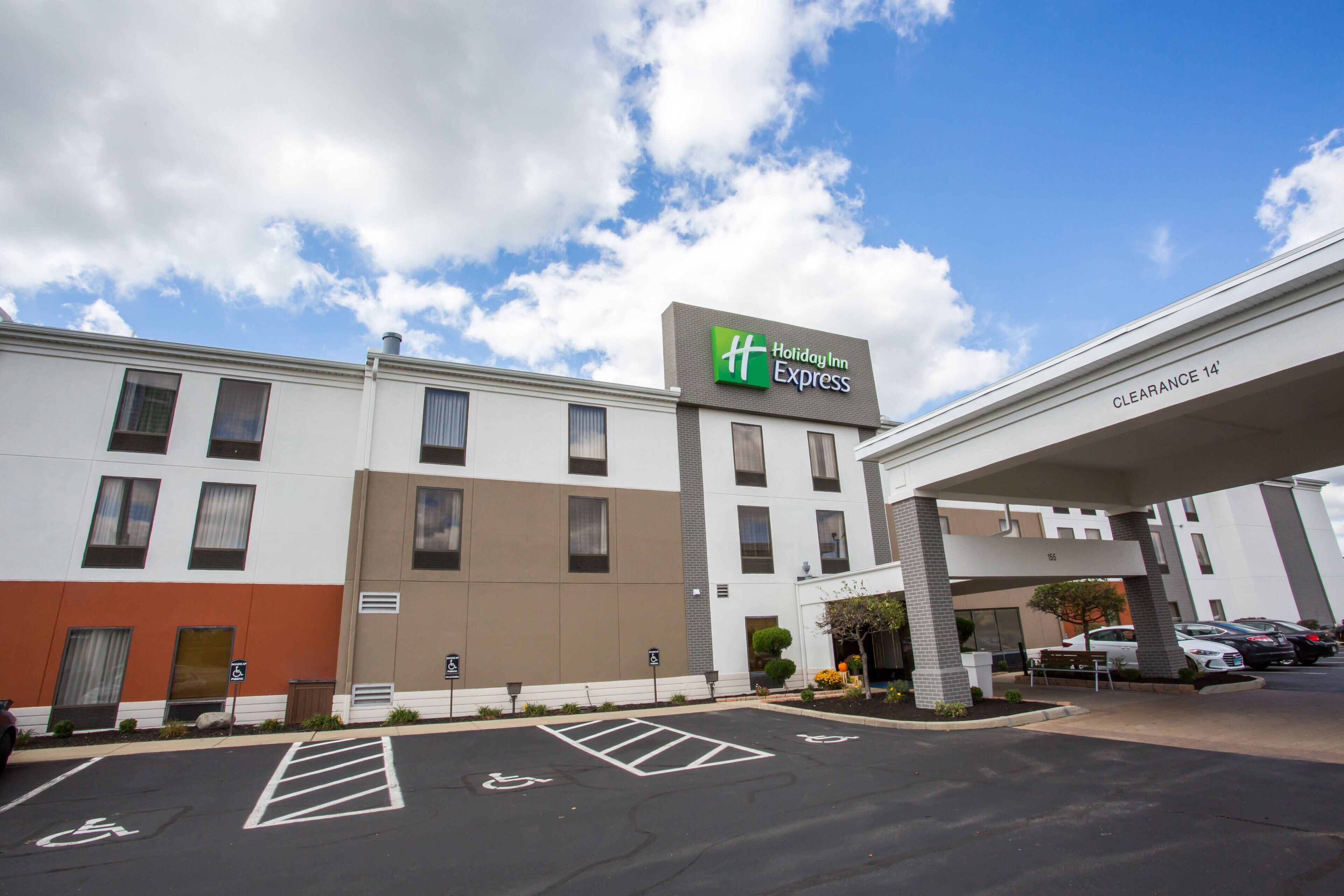 Edificio de Holiday Inn Express con cielo despejado, estacionamiento y espacios de estacionamiento accesibles para personas con discapacidad.