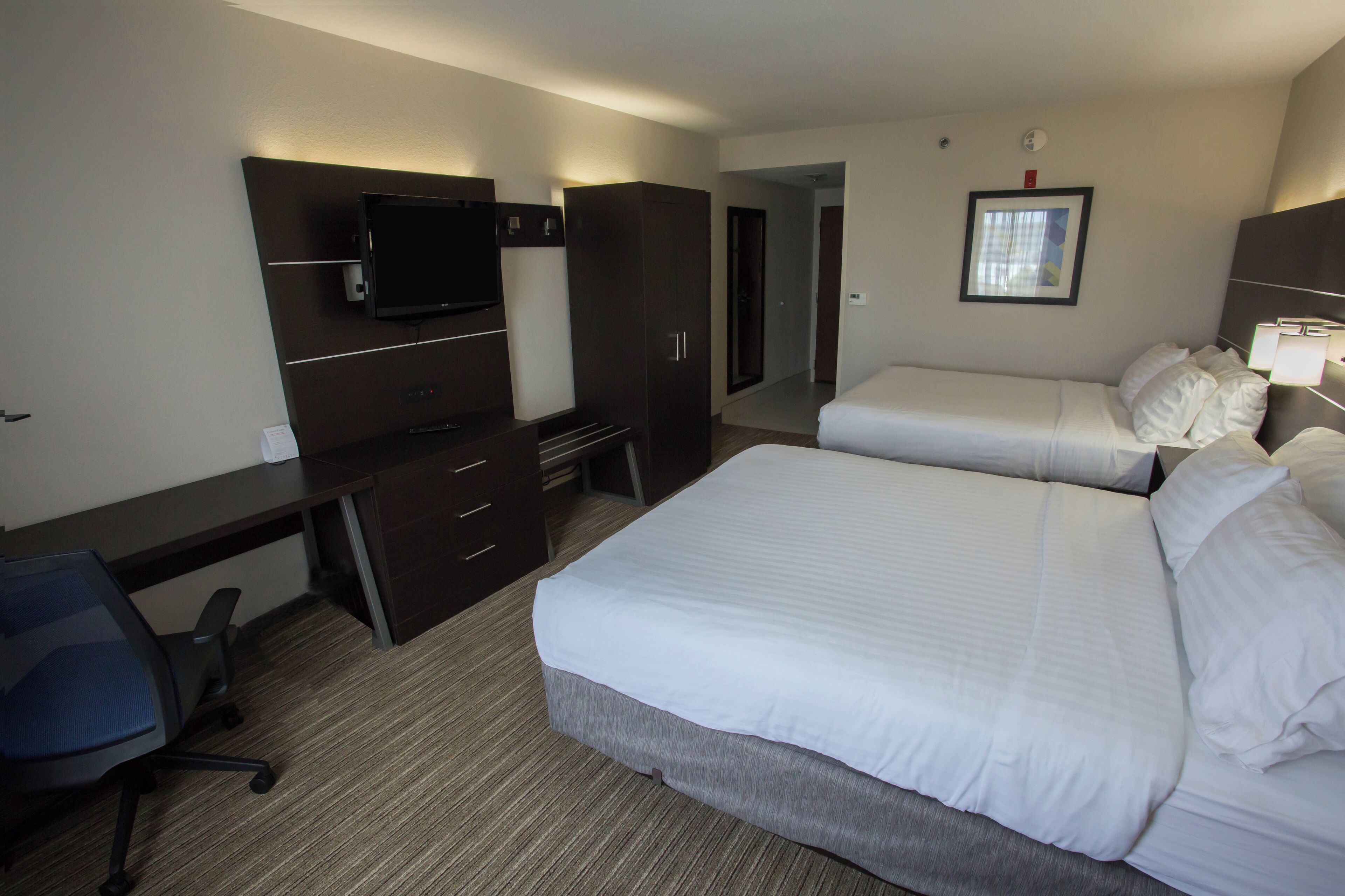 Una habitación de hotel con cama, escritorio, televisor y armario.