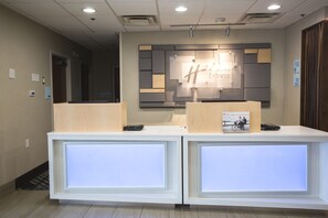 A reception desk with a sign for Holiday Inn Express, a printer, and a check-in counter.