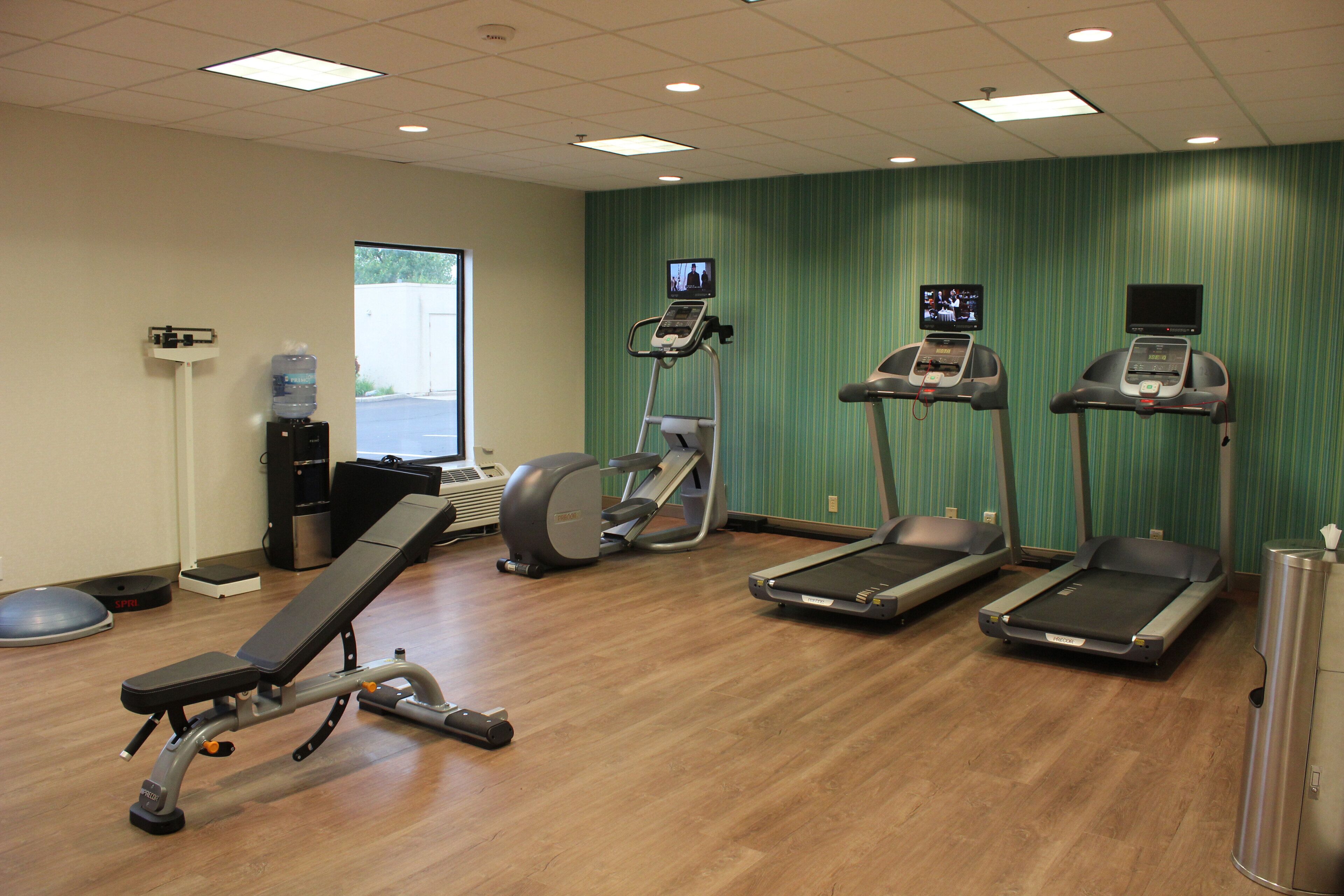 Un gimnasio con cintas de correr, una bicicleta estática y una máquina de remo.