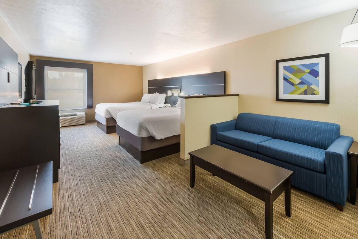 A hotel room with a bed, a sofa, a desk, and a TV.