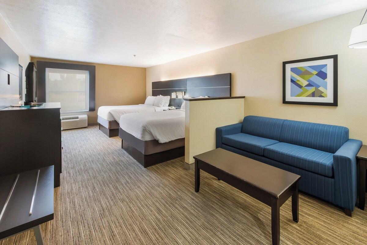 A hotel room with a bed, a sofa, a desk, and a TV.