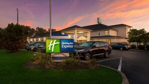 A Holiday Inn Express sign with a parking lot and a building in the background.