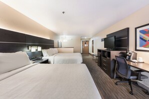 Una habitación de hotel con dos camas, un escritorio con computadora, televisor y cafetera.