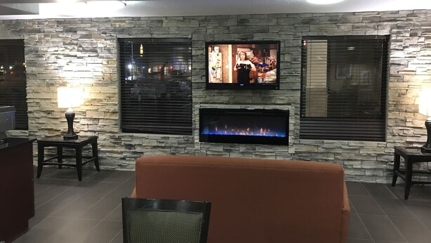 A living room with a stone wall, a flat-screen TV mounted above a fireplace, and a sofa.
