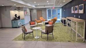 A modern lounge area with seating arrangements, a coffee station, and a reception desk. - Spark by Hilton Lancaster (Lancaster)