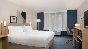 A hotel room with a large bed, a desk with a computer, a chair, and a TV.