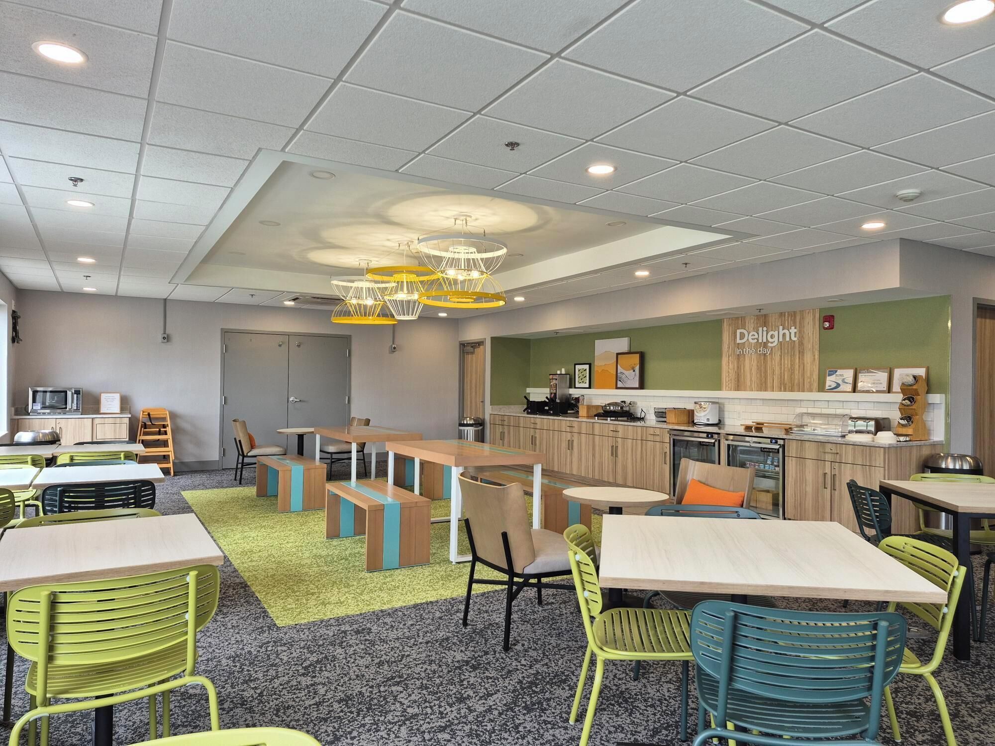 A modern kitchen area with a 'Delight' sign, wooden cabinets, and various kitchen appliances.