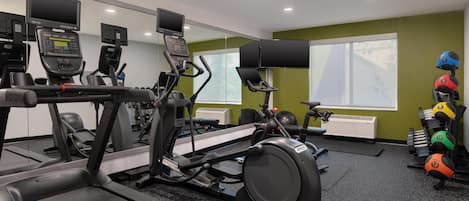 Une salle de sport équipée de tapis de course, de vélos elliptiques et de matériel de musculation.