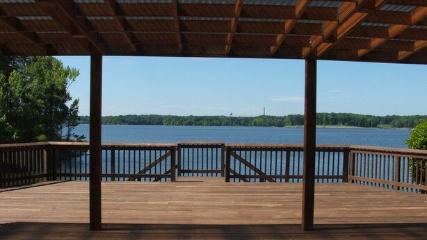 Une terrasse en bois surmontée d’un toit en métal, d’où l’on a vue sur un lac.