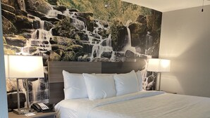 Une chambre d’hôtel avec un grand lit, deux lampes de chevet, un téléphone et une table de chevet.