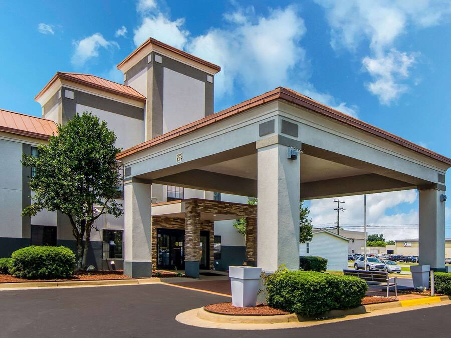 A hotel with a covered entrance, a parking lot, and a clear sky.