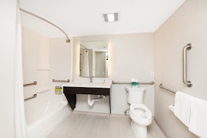 A modern bathroom with a bathtub, toilet, and sink. It includes grab bars and a shower curtain. - Holiday Inn Express & Suites Delafield by IHG (Delafield)