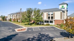 A Holiday Inn Express building with a parking lot, marked handicapped spaces, and a landscaped area with trees. - Holiday Inn Express & Suites Delafield by IHG (Delafield)
