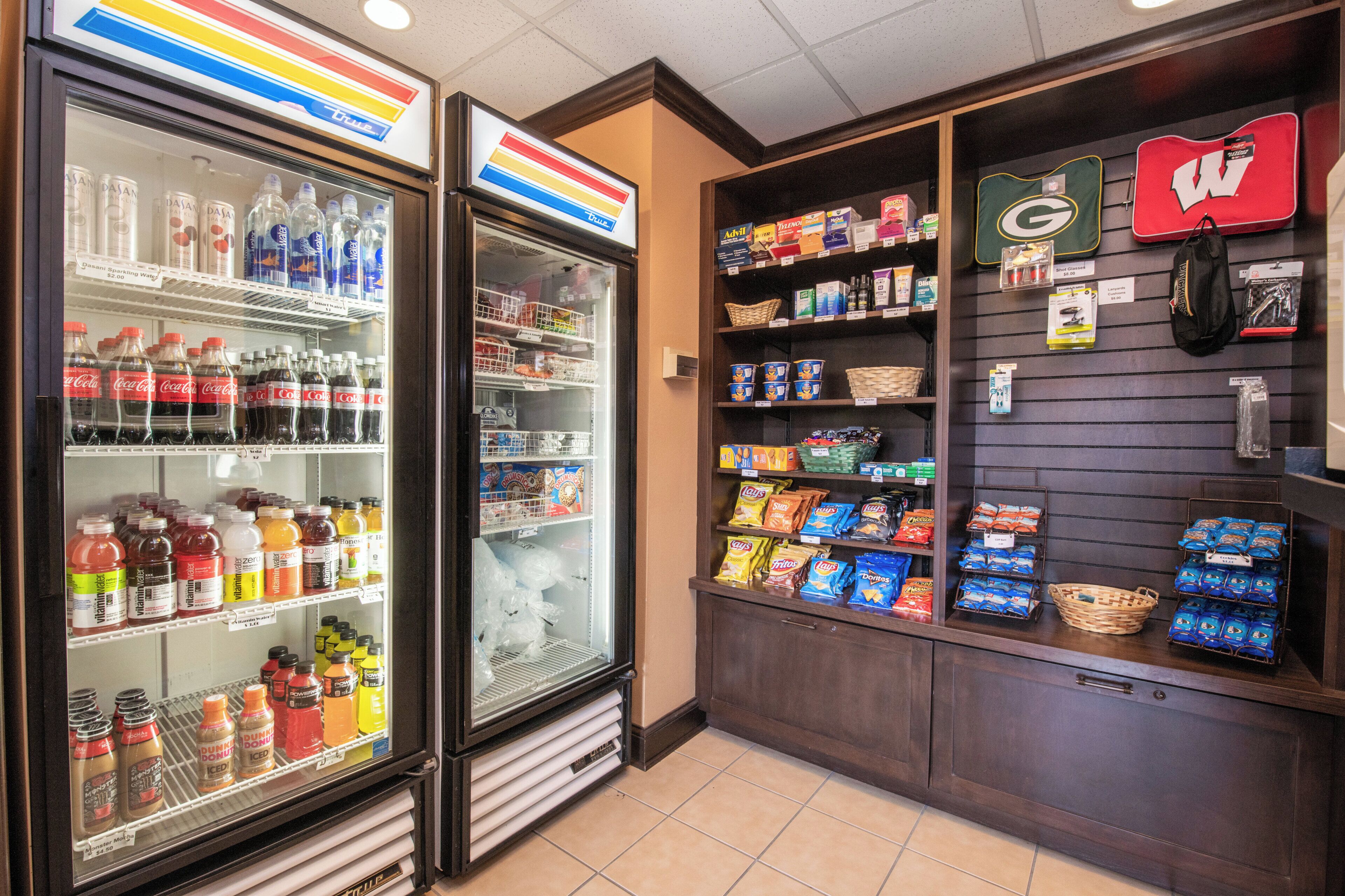 A convenience store with refrigerated drinks, snacks, and a sports jersey display.